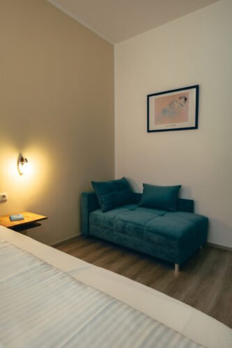 Premium-Zimmer im B&B Number 1 Bad Loipersdorf mit moderner Couch und stimmungsvoller Beleuchtung.