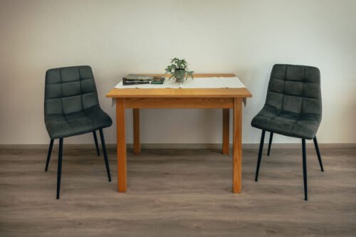 Wohnbereich des Premium-Zimmers im B&B Number 1 Bad Loipersdorf mit Designerstühlen, Holztisch und Smart-TV