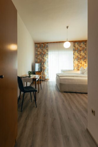 Premium-Zimmer im B&B Number 1 Bad Loipersdorf mit Boxspringbett, Schreibtisch und bodentiefen Fenstern.