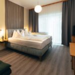 Geräumiges Premium-Zimmer im B&B Number 1 Bad Loipersdorf mit Boxspringbett, Vorraum und modernem Lamellendesign
