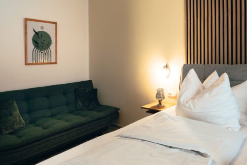 Premium-Zimmer im B&B Number 1 Bad Loipersdorf mit komfortablem Boxspringbett, Holzlamellen-Wandelement und stimmungsvoller Beleuchtung.