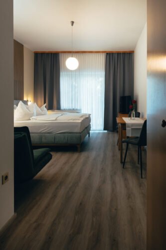 Wohnbereich des Premium-Zimmers im B&B Number 1 Bad Loipersdorf mit Designerstühlen, Holztisch und Smart-TV