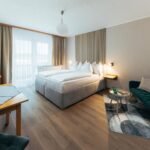 Geräumiges Premium-Zimmer im B&B Number 1 Bad Loipersdorf mit Boxspringbett, Vorraum und modernem Lamellendesign